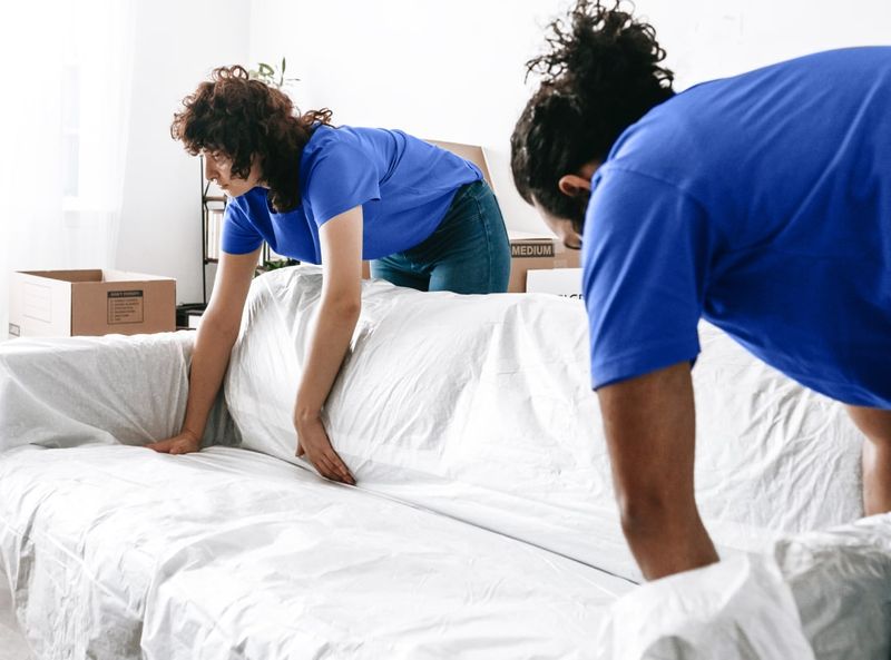 Movers4You crew wrapping a sofa for transport